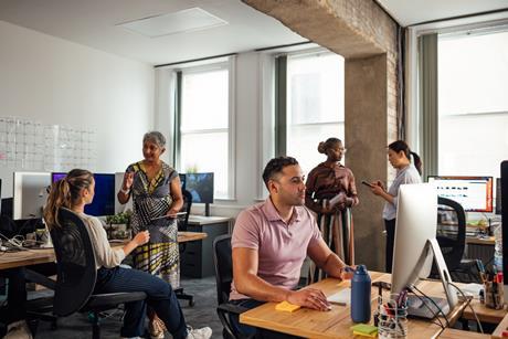 An office full of people collaborating or working on computers
